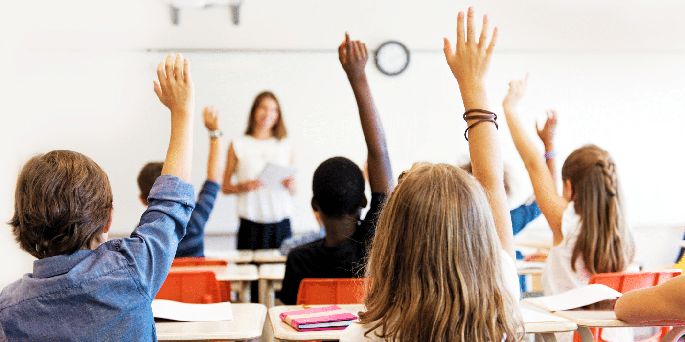 Children in class raising hands