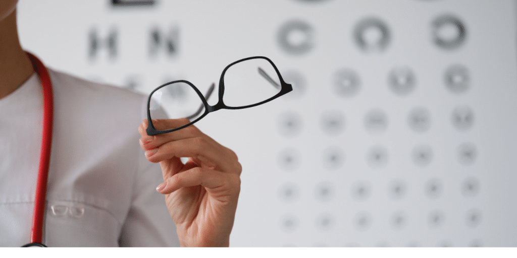 Doctor holding glasses at vision exam