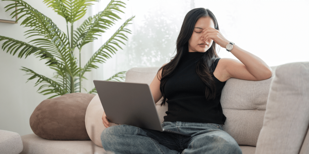 Woman with laptop rubbing her sore eyes